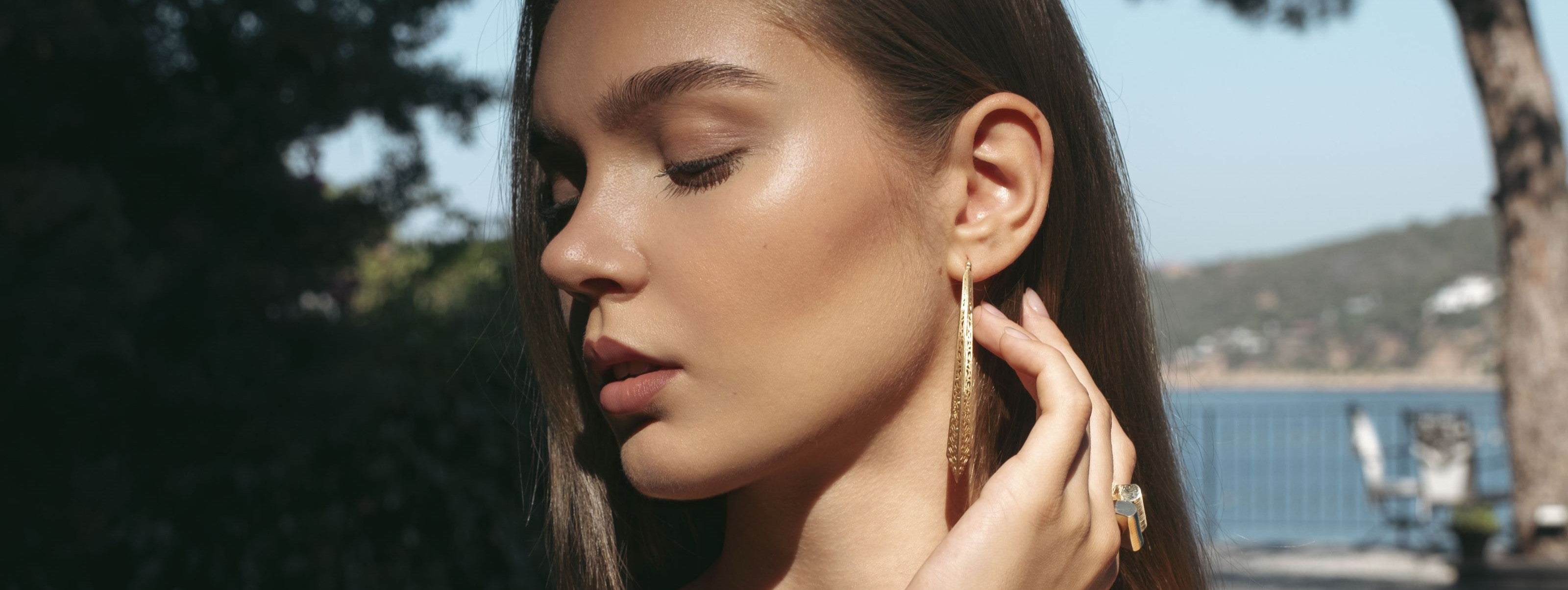 Woman wearing gold hoop earrings outdoors with blurred background